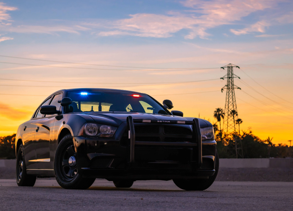 Black police vehicle parked in front of a sunset with palm trees